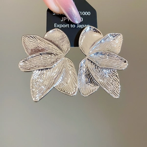 Detailed view of silver petal earrings with textured metal finish and artistic design
