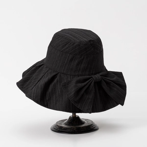 Detail of elegant black wide-brim sun hat with oversized bow and pleated texture