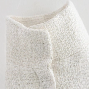 Close-up of cream tweed poncho coat showing intricate woven fabric and collar details