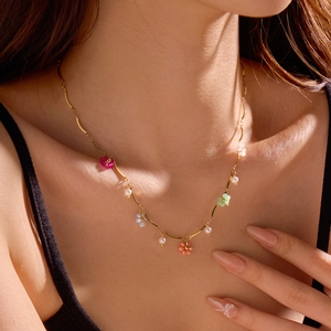Elegant gold chain necklace featuring colorful floral charms and delicate white pearls