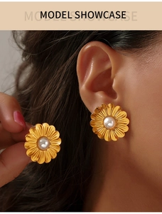 Détail de boucles d'oreilles marguerites vintage avec pétales dorés et perle blanche