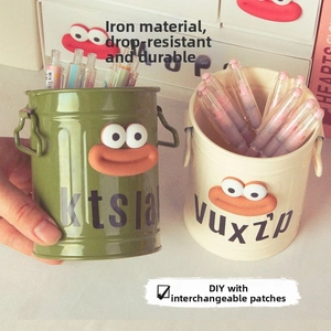 Detail of iron pencil holder with cartoon 3D eyes and lips, green and beige colors