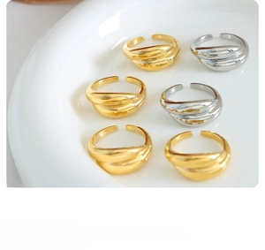 Detailed close-up of six-piece adjustable ribbed gold and silver rings on white ceramic