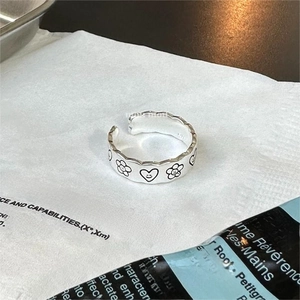 Close-up of S925 silver ring with sunflower and smiley heart engraving on textured paper