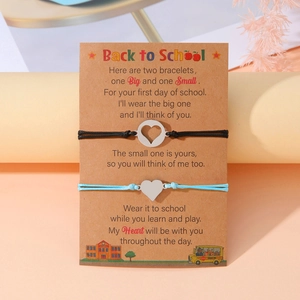 Dettaglio di bracciali a cuore madre-figlia su biglietto Back to School con poesie