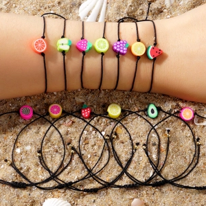 Braccialetti intrecciati in argilla polimerica alla frutta su spiaggia sabbiosa