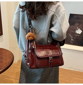 Detailed view of a vintage wine red leather tote bag with plush puppy pendant accessory