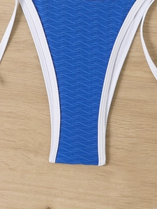 Detail of blue wavy textured bikini fabric with white trim on light wooden background