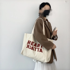 Large cream canvas tote bag with red letter print shown on model shoulder