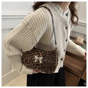 Detail of leopard print hobo bag featuring a silver metal bow and plush texture