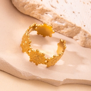 Macro shot of gold hollow flower star ring displayed on a natural beige stone texture