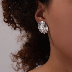 Vintage silver spiral texture stud earrings with central pearl on model's ear