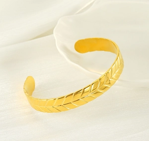 Detailed view of adjustable wheat ear pattern gold bangle on white silk background