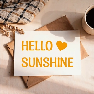 Detail showing HELLO SUNSHINE vinyl sticker on card with morning coffee aesthetic