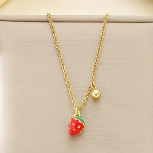 Detailed view of a sweet gold strawberry pendant necklace with red enamel and white dots