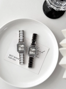 Close-up of square diamond-encrusted watch case and mixed-link metal strap on ceramic