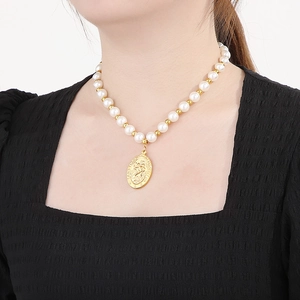Détail du pendentif Saint Christophe en or sur collier de perles porté par un mannequin