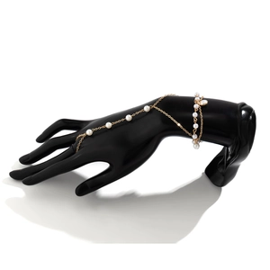 Detail of gold metal hand chain with white pearls on a professional studio mannequin