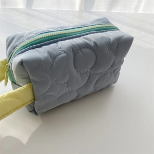 Close-up of cloud quilting pattern on a light blue polyester cosmetic bag with yellow handle