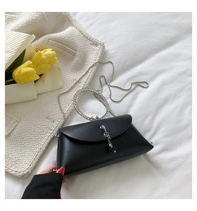 Detail of black trapezoid evening bag with rhinestone handle and silver metal chain strap