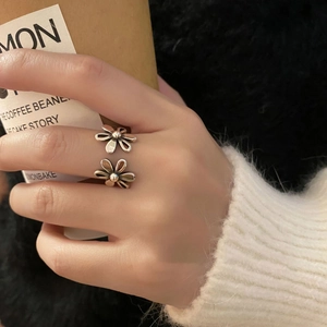 Macro view of adjustable silver ring with dual floral daisy design on female finger