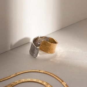 Detail of two-tone gold and silver wide ring with hammered metal texture and wavy design