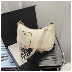 Detail view of cream-white square shoulder bag featuring front flap pocket and zipper closure