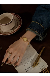 Close-up of golden vintage-style quartz watch with slim metal strap on a woman's wrist