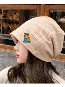 Close-up of beige knit beanie featuring a Purrrsist cat badge on a side view model