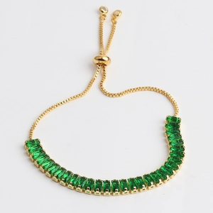 Detail of adjustable gold tennis bracelet with emerald green rectangular cubic zirconia