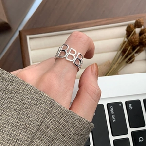 Detailed view of silver hollow B letter ring worn in a professional office setting