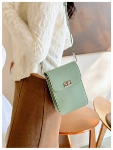 Pale green mini leather phone bag with gold metal buckle shown on a model's side