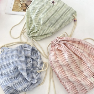 Close-up of drawstring plaid canvas bags in green, blue, and orange pastel colors