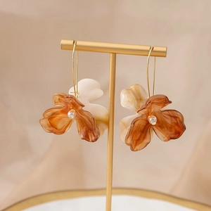 Retro amber flower earrings with pearl accents hanging on a golden display stand