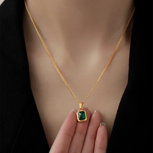 Elegant gold chain necklace featuring a rectangular emerald green gemstone pendant on model