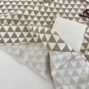 Detail of cotton linen tablecloth showing brown geometric triangles and hemmed edges