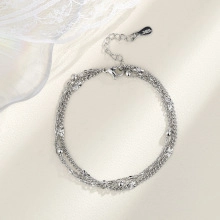 Detailed close-up of multi-layer silver S925 bracelet with beads and lace background