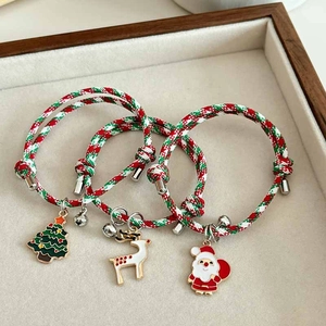 Close-up of woven Christmas bracelets with enamel Santa, tree, and elk charms