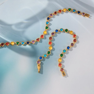Detail view of gold-plated bracelets featuring heart-shaped rainbow crystals on blue water