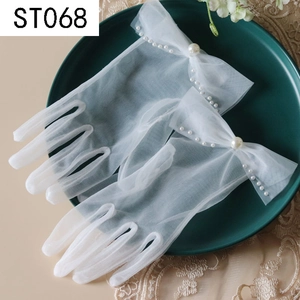 Detail of white tulle bridal gloves with pearls on a dark green ceramic plate