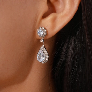 Macro detail of teardrop zircon earring set in silver finish on a model's ear