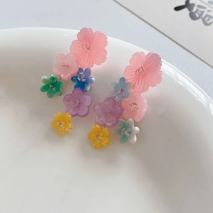 Macro shot of colorful resin floral drop earrings in pink and blue on white ceramic