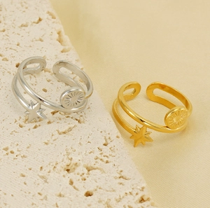 Detail of 18K gold and silver star rings with sunburst pendant on stone background