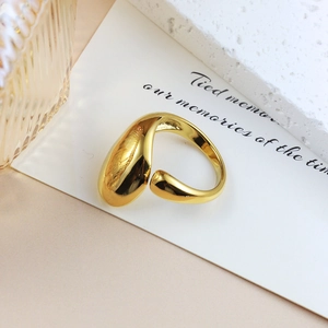 Detail view of a gold minimalist open ring with irregular curved design on a paper card