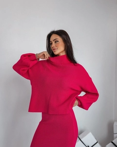 Gros plan sur la texture en maille côtelée fuchsia de l'ensemble pull et jupe