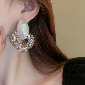 Macro view of luxurious pearl and rhinestone heart earring on model earlobe