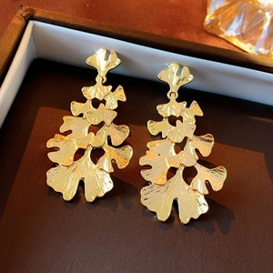 Macro view of gold ginkgo leaf earrings with detailed veins on a black velvet jewelry box