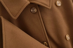 Close-up of brown wool coat featuring textured fabric, lapel and amber buttons