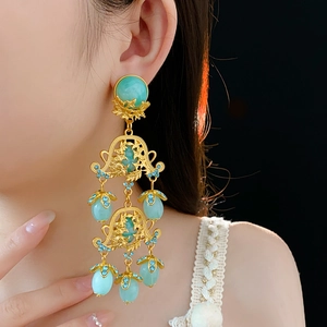 Close-up of vintage gold floral earrings with turquoise beads and blue rhinestones on model