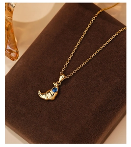 Detailed view of gold croissant pendant necklace with a blue gemstone center stone